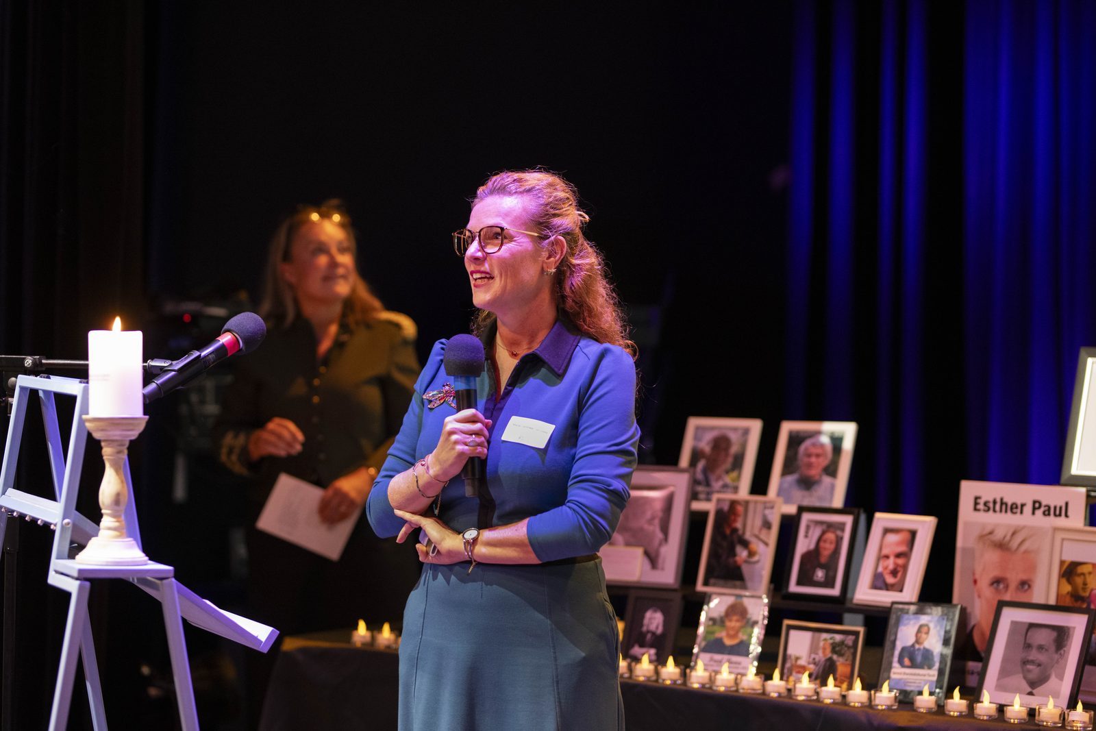 Marije op het podium bij de foto's van slachtoffers